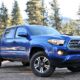 Front angle view of blue Toyota Tacoma in front of the forest