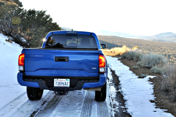Tailgate of Toyota Tacoma driving down snowy mountain road
