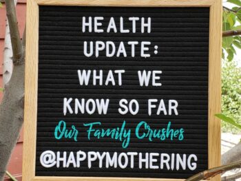 Sign that reads, "Health Update: What We Know So Far; Our Family Crushes; @HappyMothering"
