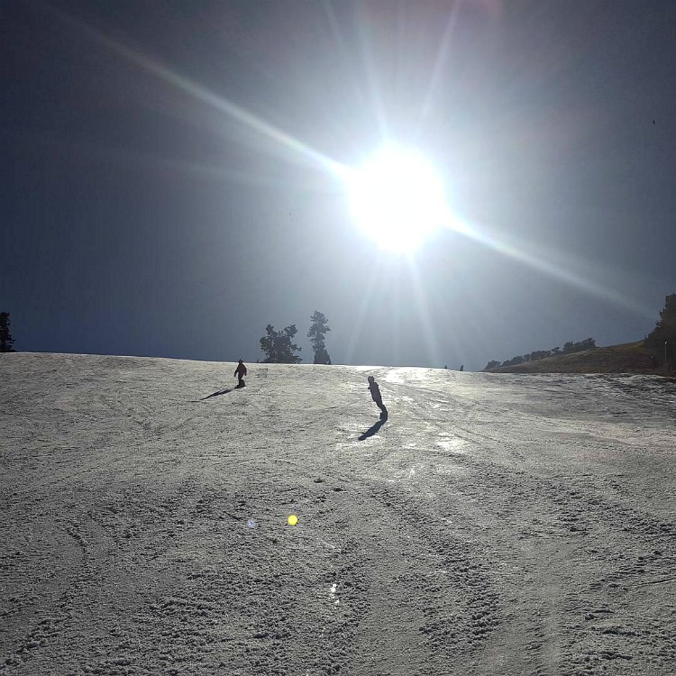 Zoe and Kaylee snowboarding at Bear Mountain with the sun in the background