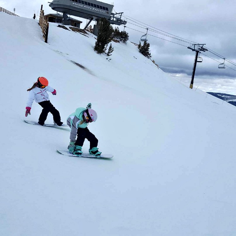 Zoe and Kaylee doing tailpresses on their snowboards