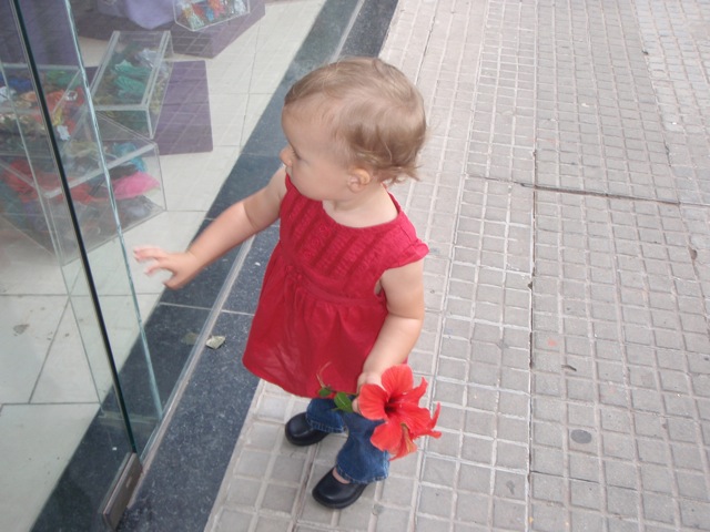 Zoë holding a red flower looking in a window