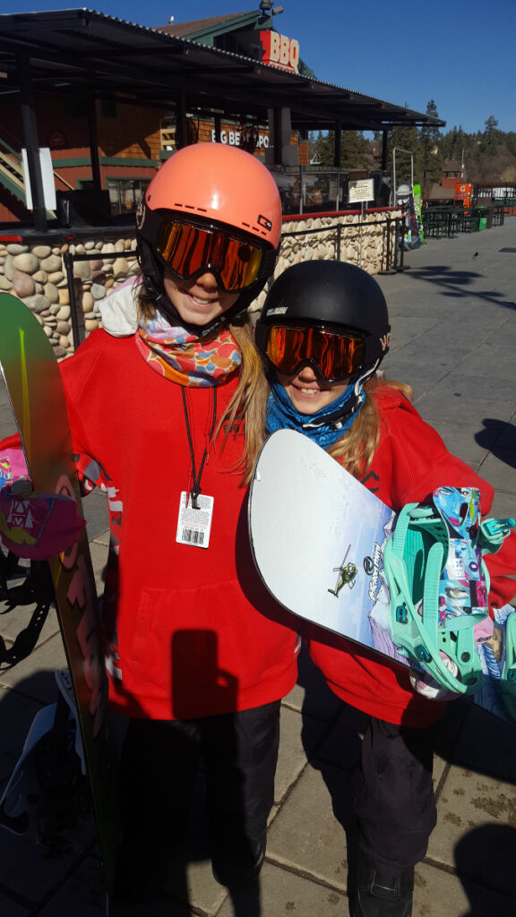 Zoë and Kaylee with their snowboards at Bear Mountain on the deck