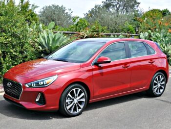 Red Hyundai Elantra GT parked on a street with lush greenery