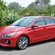 Red Hyundai Elantra GT parked on a street with lush greenery