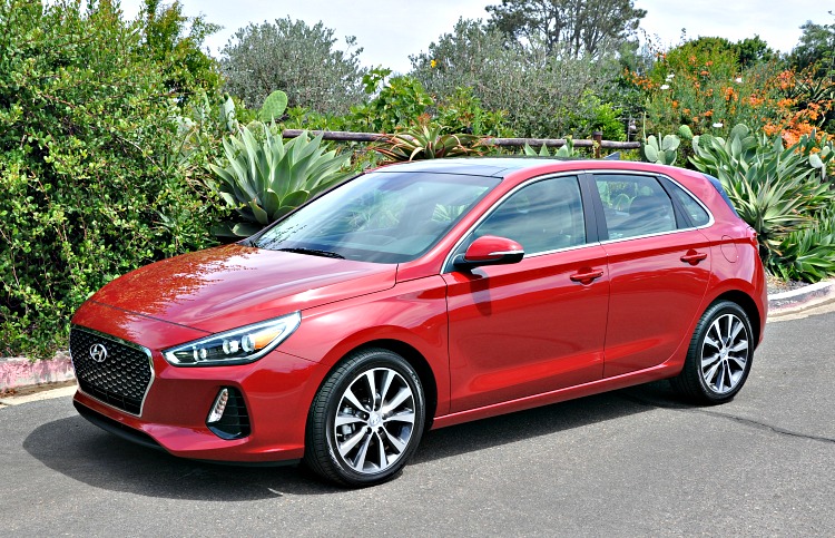 Red Hyundai Elantra GT parked on a street with lush greenery