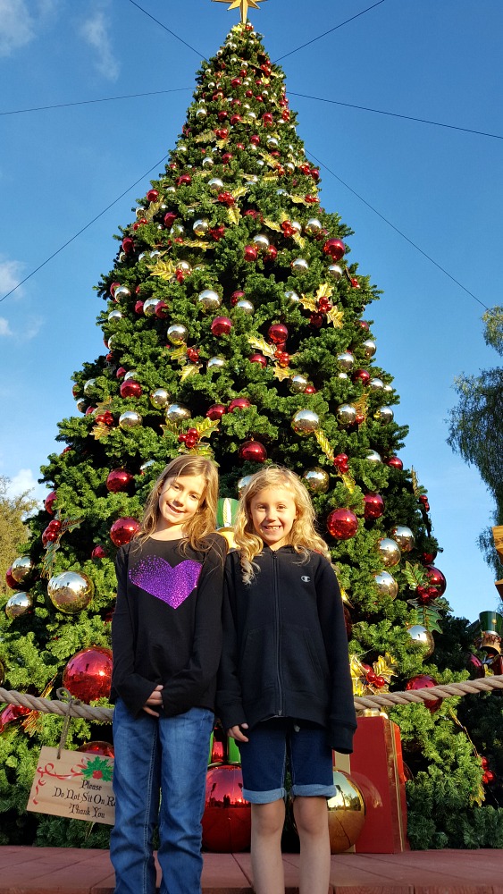 Zoë and Kaylee in front of the Christmas tree during the day at Knott's Merry Farm