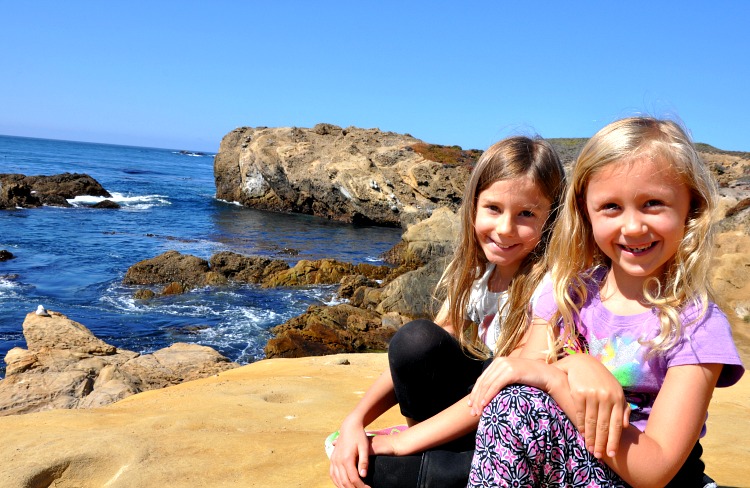 Zoë and Kaylee sitting on the cliffs at Point Lobos State Reserve on our family trip