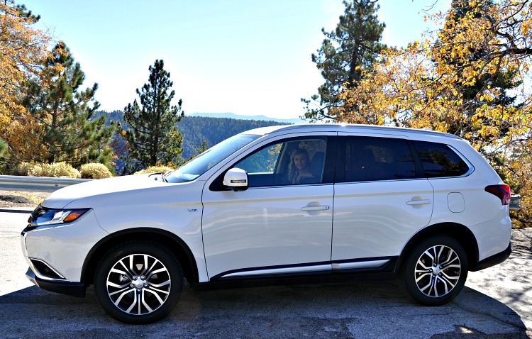 Side of the Mitsubishi Outlander with mountains and trees in the background