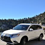 2018 White Mitsubishi Outlander with mountains and blue sky behind it