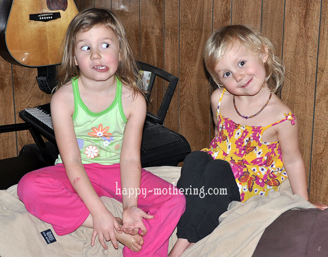 Zoë and Kaylee sitting on the brown couch making goofy faces for the camera