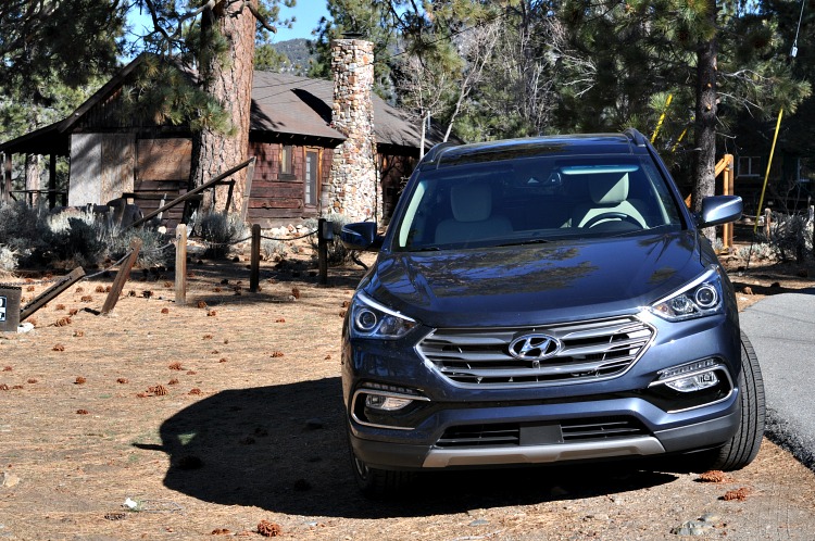 Hyundai Santa Fe Sport parked in front of an old cabin by the lake
