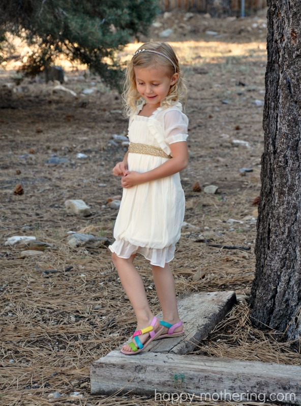 Kaylee glancing at the ground on a beam in her handmade Christmas dress