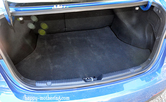 Blue Kia Forte with open trunk