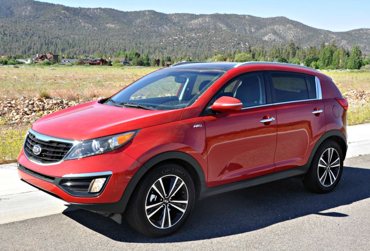 Red Kia Sportage with grassy fields behind it