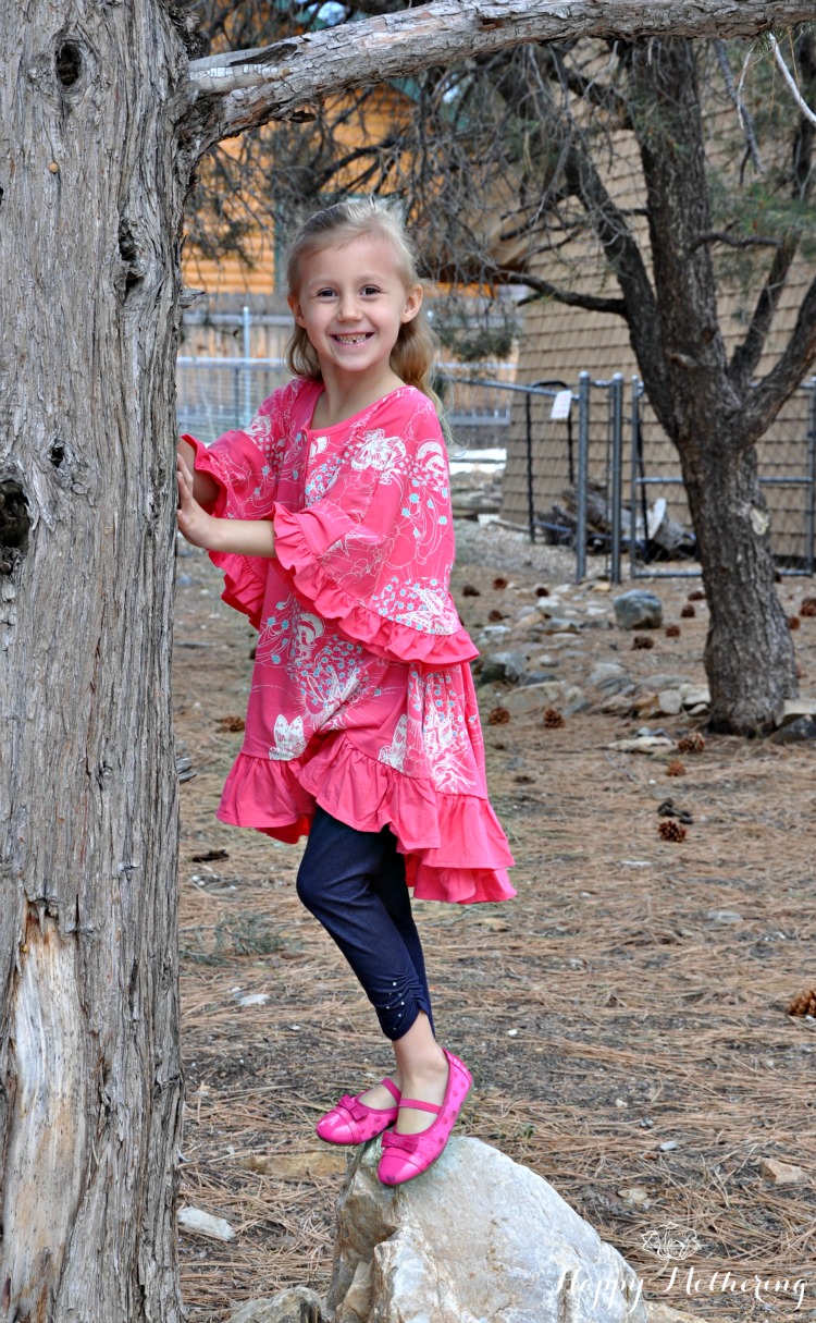 Kaylee under a tree on a rock wearing Little Skye Boutique clothes