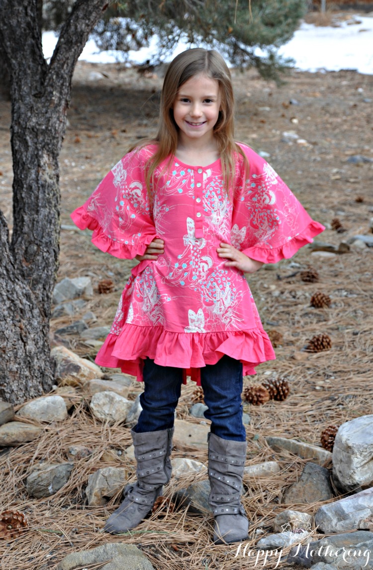 Zoë standing with her hands on her hips under a tree