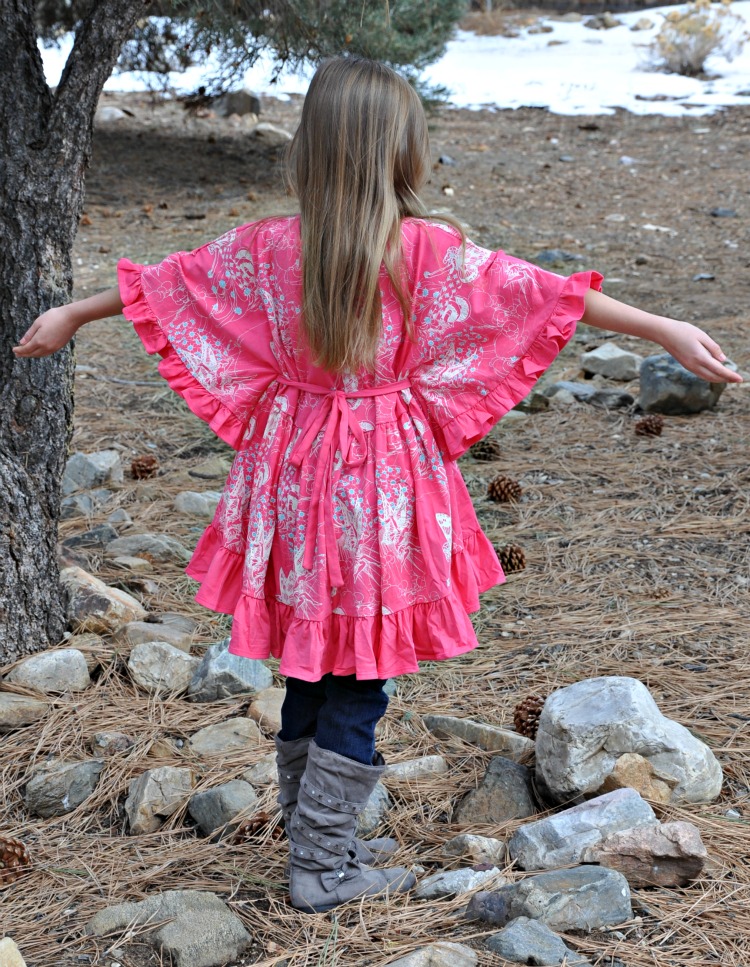 Zoë standing with her arms spread wide to show off the back of the Little Skye Boutique top