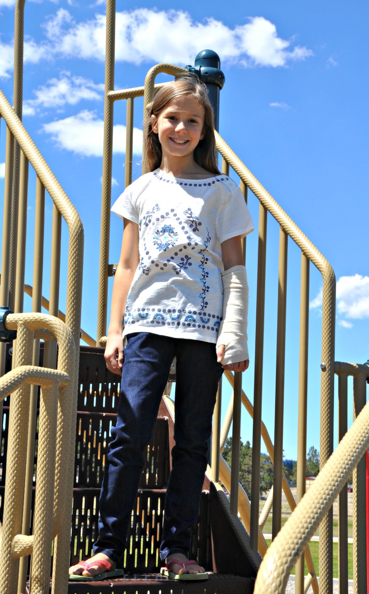 Zoë standing on the stairs to the slide at the park
