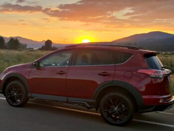 Red Toyota RAV4 at sunset with mountain in the background