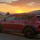 Red Toyota RAV4 at sunset with mountain in the background