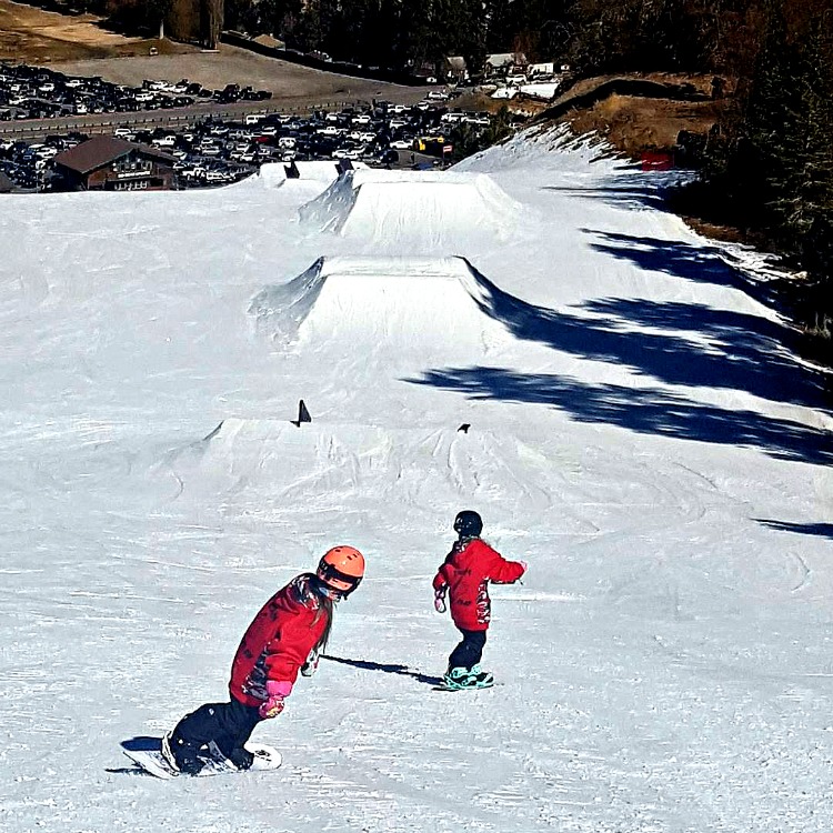 Zoë and Kaylee snowboarding on the Slope Style course